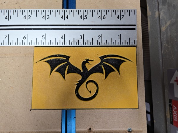 Dragon silhouette cut from gold plastic next to a ruler