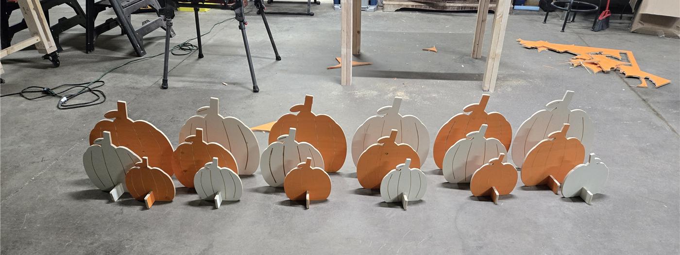 Eighteen painted wooden pumpkins in three sizes on the shop floor